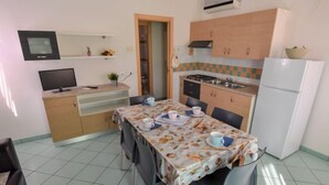 A compact kitchen with a dining area, a TV, and a refrigerator. - Solmare by Interhome (Rosolina Mare)