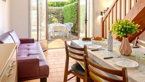 A dining area with a table set for two, a sofa, and a staircase leading to an upper level. - Vacation home Sicard by Interhome (Mimizan)