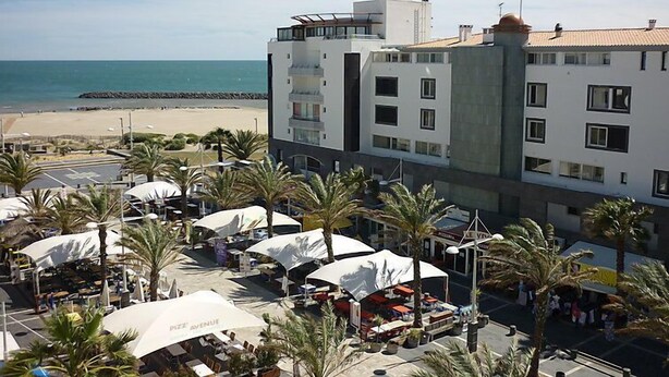 Een hotel aan het strand met meerdere verdiepingen, buiten zitgedeeltes en uitzicht op de oceaan.