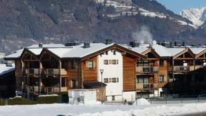 Eine Reihe von Holzhütten mit Balkonen vor einer schneebedeckten Berglandschaft.