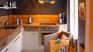 Una cocina moderna con detalles de madera, electrodomésticos de acero inoxidable y un comedor con una mesa lista para dos personas.
