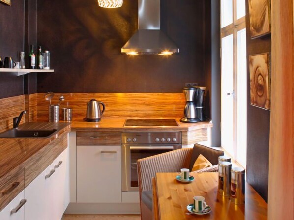 A modern kitchen with wooden accents, stainless steel appliances, and a dining area with a table set for two.