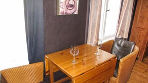 Una mesa de madera con dos sillas, un cuadro de una rosa en la pared y una ventana con cortinas.