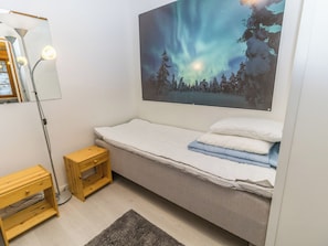 Une chambre à coucher avec un lit, une table de chevet, une lampe et un tableau représentant des aurores boréales accroché au mur.