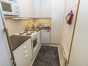 A compact kitchen with a microwave, stove, sink, and a dishwasher.