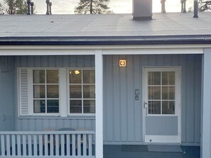 A two-story building with a porch, a door marked with a 'C3' sign, and a window with shutters.