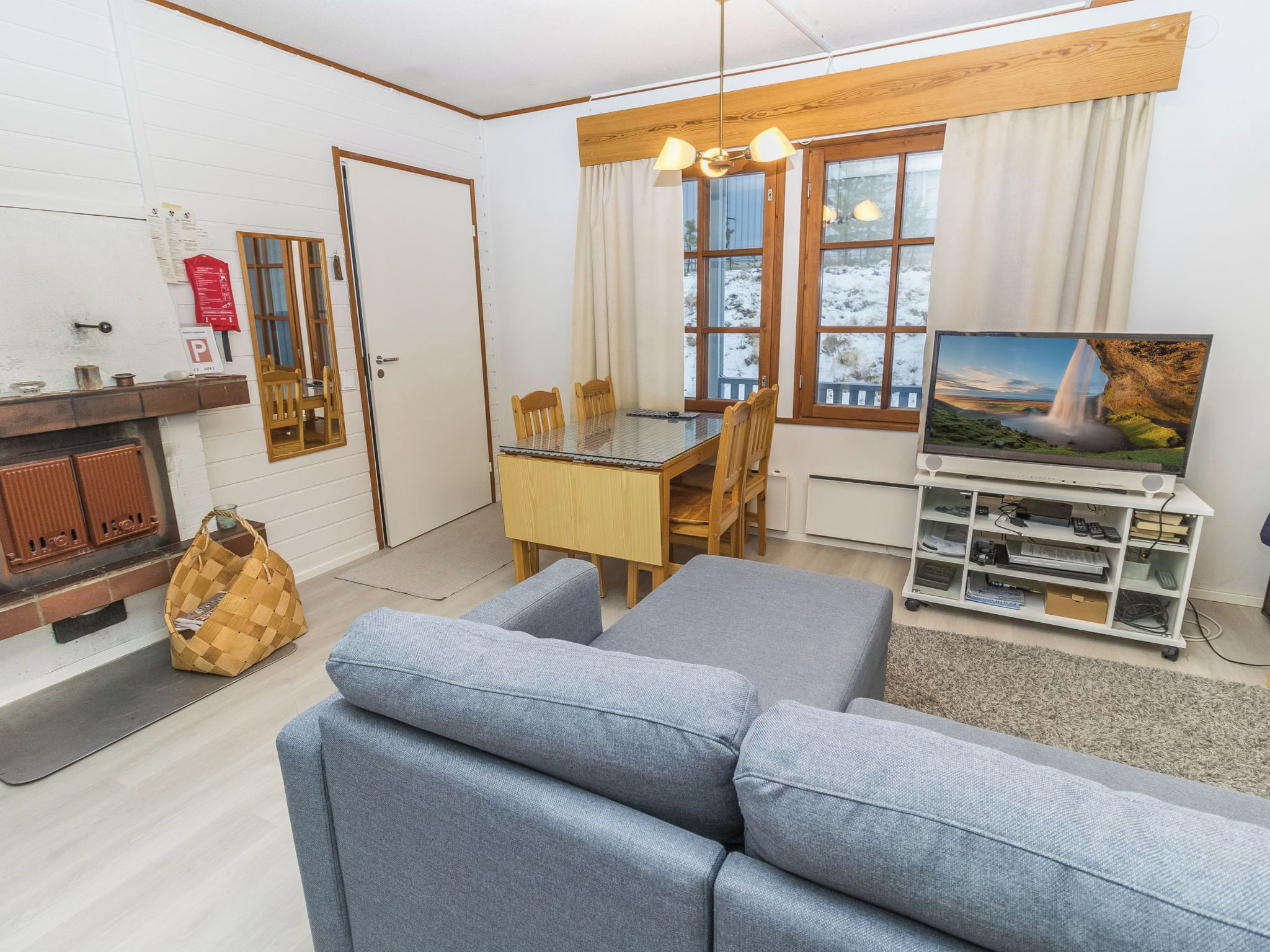 Een woonkamer met een bank, een eettafel met stoelen, een televisie en een open haard.