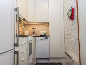 A compact kitchen with a dishwasher, a coffee machine, and a kettle.