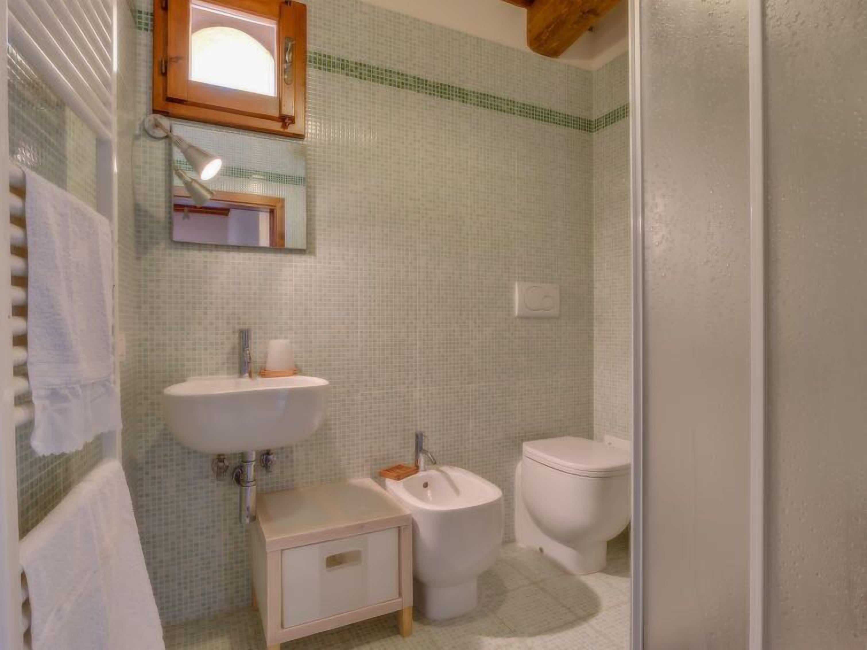 Een badkamer met een wastafel, spiegel en toilet.