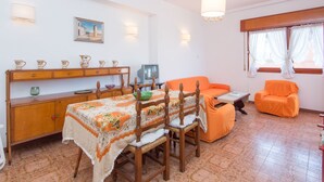 A cozy living room with a dining table, orange sofa, and a television.