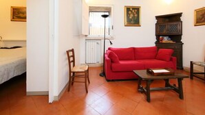 A living room with a red sofa, a wooden chair, a small table, and a cabinet. - Pantheon by Interhome (Rome: Historical City Center)