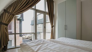 Une chambre avec deux lits, une grande fenêtre avec des rideaux et une armoire.