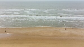 Une plage avec une vaste étendue de sable et l’océan en toile de fond.