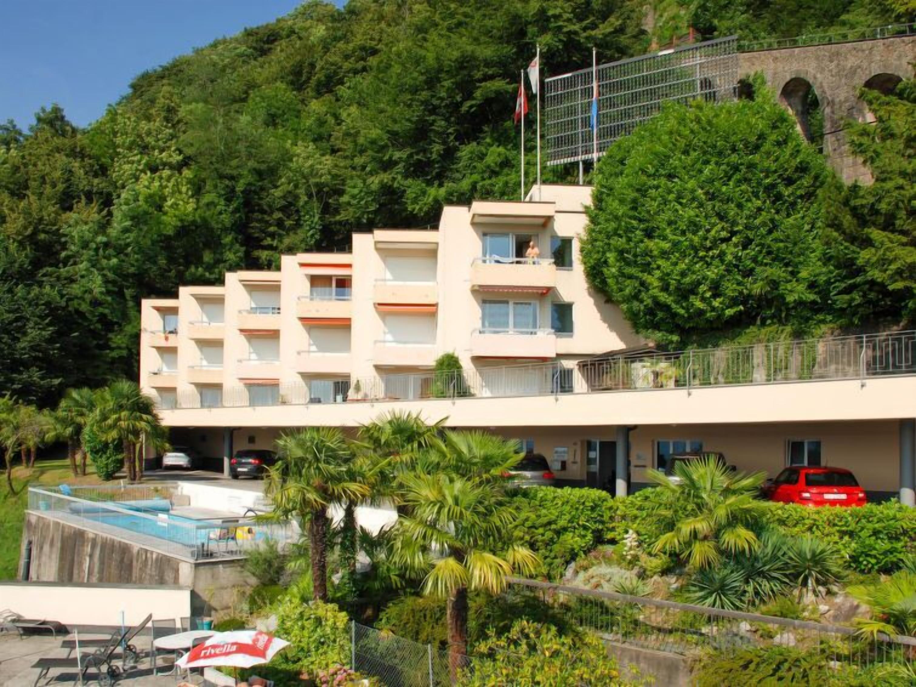 Un hôtel à plusieurs étages doté de balcons, d’une piscine et d’une végétation luxuriante.