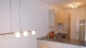 Una cuina compacta amb taula i cadira, forn integrat i cafetera.