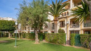 Un edificio residenziale con diversi balconi, un prato curato e una varietà di alberi e arbusti.