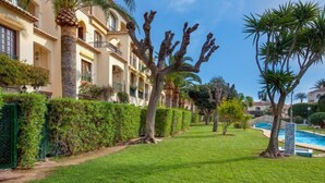 Cortile di un hotel ben curato, con piscina, siepi ordinate e palme.