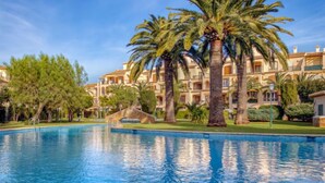 Una piscina circondata da palme e un edificio con balconi.