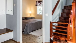 A bedroom with a bed, a nightstand, a lamp, and a window with curtains.