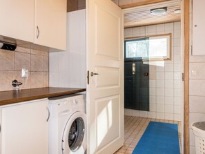 A laundry area with a washing machine, a door leading to a shower, and a window. - Levijoutsen by Interhome (Kittilä)
