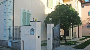 A building with a gated entrance, a tree in front, and a clear sky. - Apartment Milano by Interhome (Forte dei Marmi)
