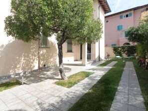A courtyard with a tree, a bicycle, and a building with a pink facade.