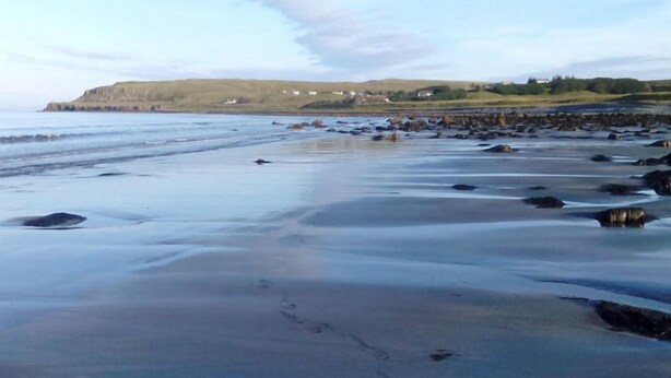 A beach with a rocky shoreline and a distant view of hills and houses. - Alan's House by Interhome (North Skye)