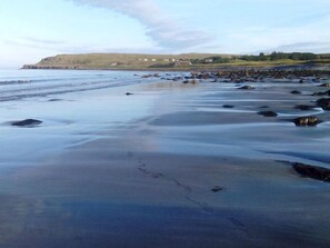 A beach with a rocky shoreline and a distant view of hills and houses.