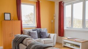 A cozy living room with a sofa, a wooden cabinet, and a small table. - Alan's House by Interhome (North Skye)