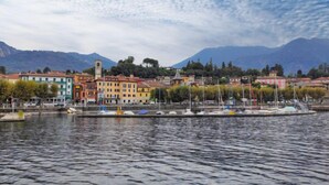 A waterfront view with colorful buildings, a dock with boats, and mountains in the background.