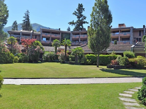 Ein Hotel mit mehreren Balkonen, üppigem Grün und blauem Himmel.