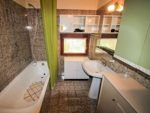 Ein Badezimmer mit Badewanne, Waschbecken und Fenster.