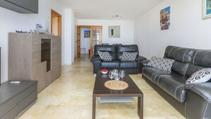 A modern living room with a leather sofa, a dark coffee table, and a TV mounted on the wall.