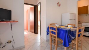 A compact living space with a dining area, kitchenette, and a television on a shelf. - Casa Daniela by Interhome (Rosolina Mare)