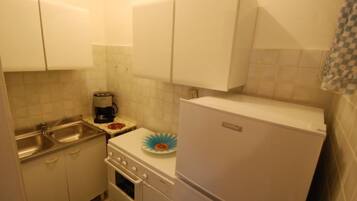 Een koelkast, een oven, kookgerei, borden en bestek