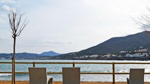 A coastal view with three concrete benches facing the sea, a wooden railing, and a mountain in the background. - Mar Nou by Interhome (Llançà)
