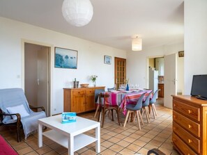 A living room with a dining area, a wooden cabinet, and a television.