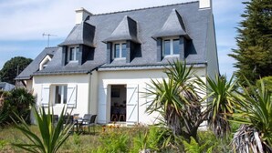 A two-story house with a sloped roof, multiple chimneys, and a front door leading to a covered porch. - Vacation home Trezen by Interhome (Carnac)