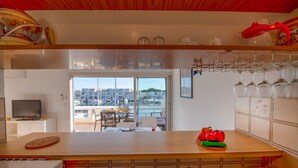 Une cuisine avec vue sur le port de plaisance, un coin repas avec une table et des chaises, et un meuble à vin avec des verres.