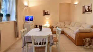 Ein gemütliches Wohnzimmer mit Esstisch, Stühlen, einer Couch und einem Fernseher.