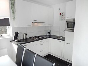 Een koelkast, een vaatwasser, kookgerei, borden en bestek