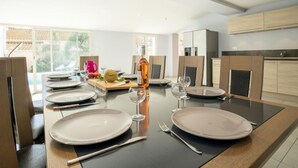 Eine moderne Küche mit Esstisch für vier Personen, einem großen Fenster und hellen Küchenschränken.