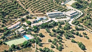 An aerial view of a residential area with multiple buildings, a tennis court, and a swimming pool.