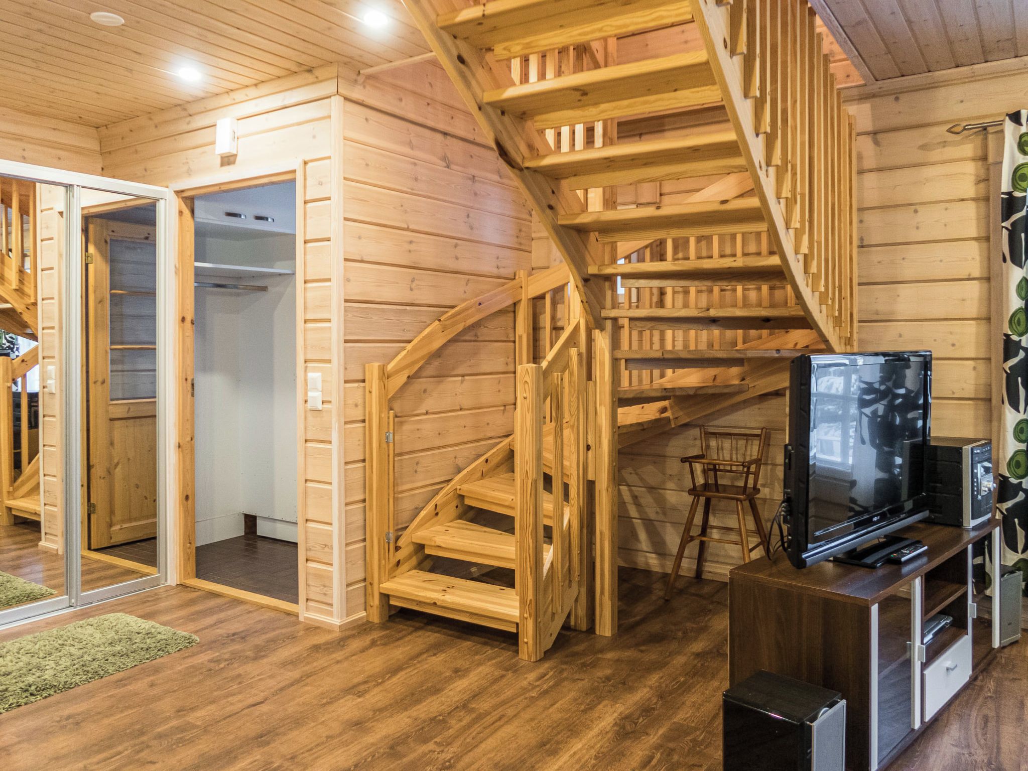 Un intérieur en bois avec un escalier, un téléviseur et un plancher en bois.