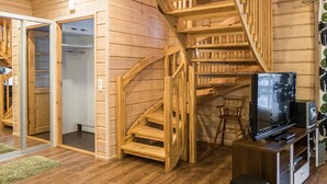 Un interior de madera con una escalera, un televisor y una pequeña zona de estar.