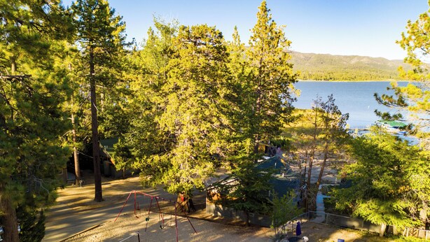 Vista de una propiedad frente al lago con piscina, un conjunto de columpios y una zona de estar cubierta.