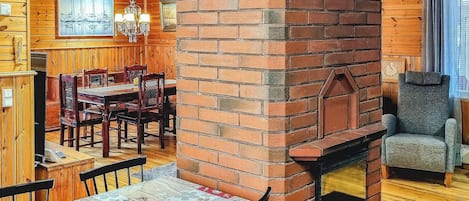 Un intérieur chaleureux avec une cheminée en briques, un coin repas en bois et un bar aux murs en bois.