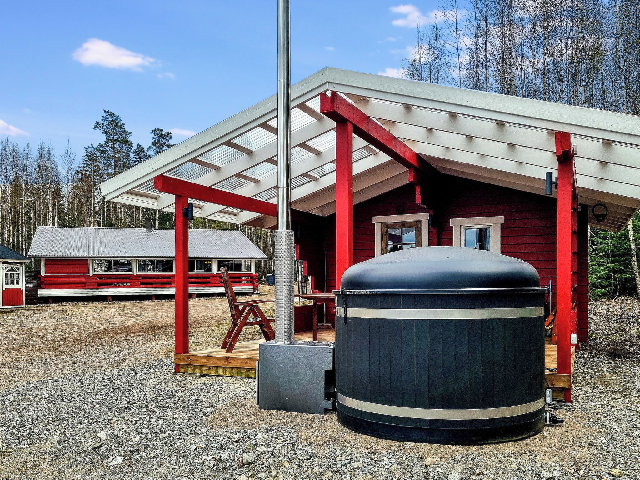 Eine rote Holzhütte mit einer überdachten Veranda und einem großen zylindrischen Tank.