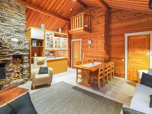A cozy cabin interior with a stone fireplace, wooden dining table, and a comfortable seating area.