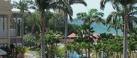 A resort with a pool, palm trees, and a view of the ocean.